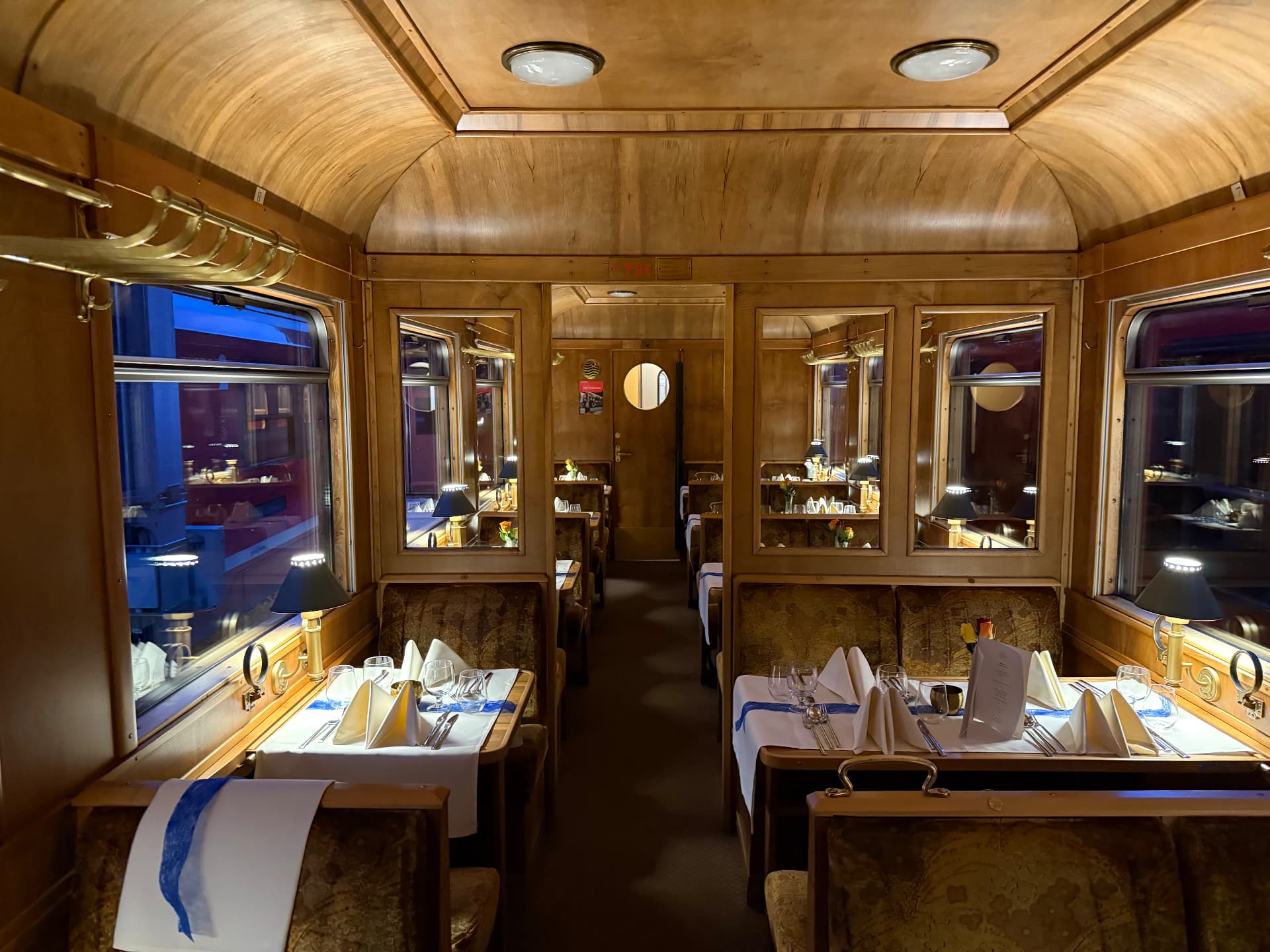 Fine Dining wagon interior with burr-wood panelling, brass luggage racks and tables laid with linen