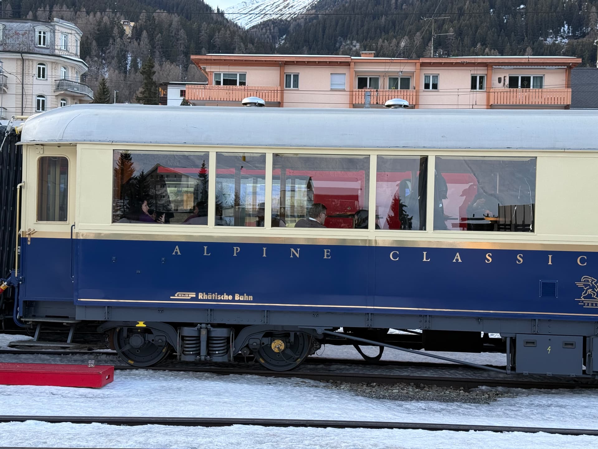 The blue and cream Alpine Classic carriage with guests seated at the windows