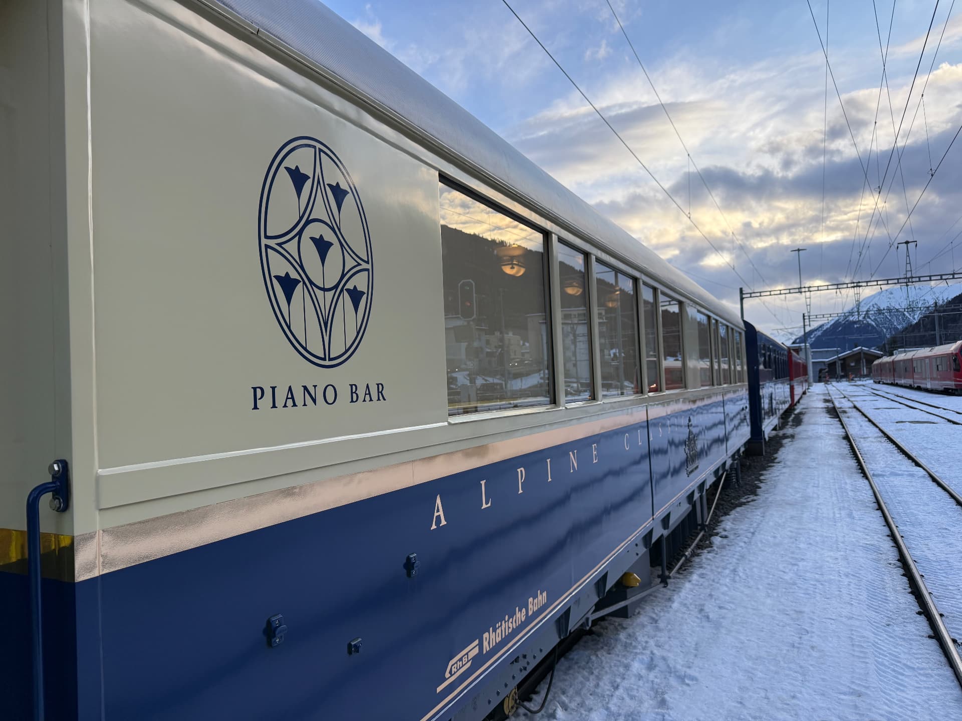 Exterior of the Piano Bar carriage in Alpine Classic blue and cream on snowy track at dusk