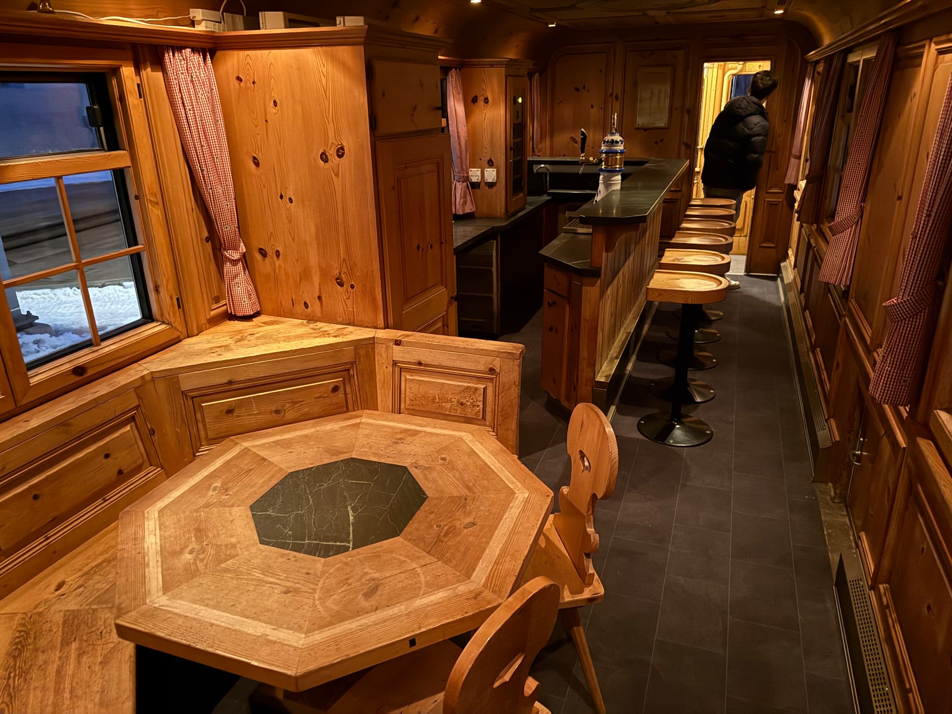 Alpine Pub with pine panelling, an octagonal stone-inlaid table and a stone-topped bar with stools