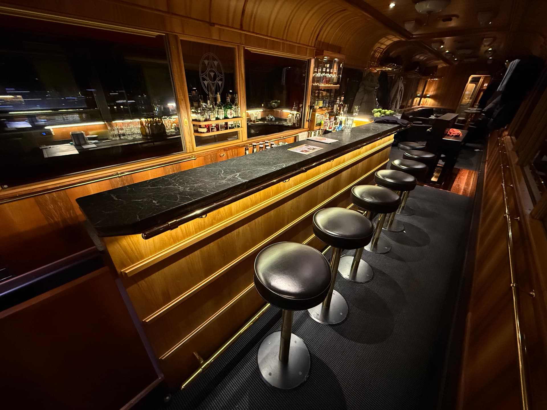The long marble bar of the Piano Bar wagon lit from beneath, stools in a row