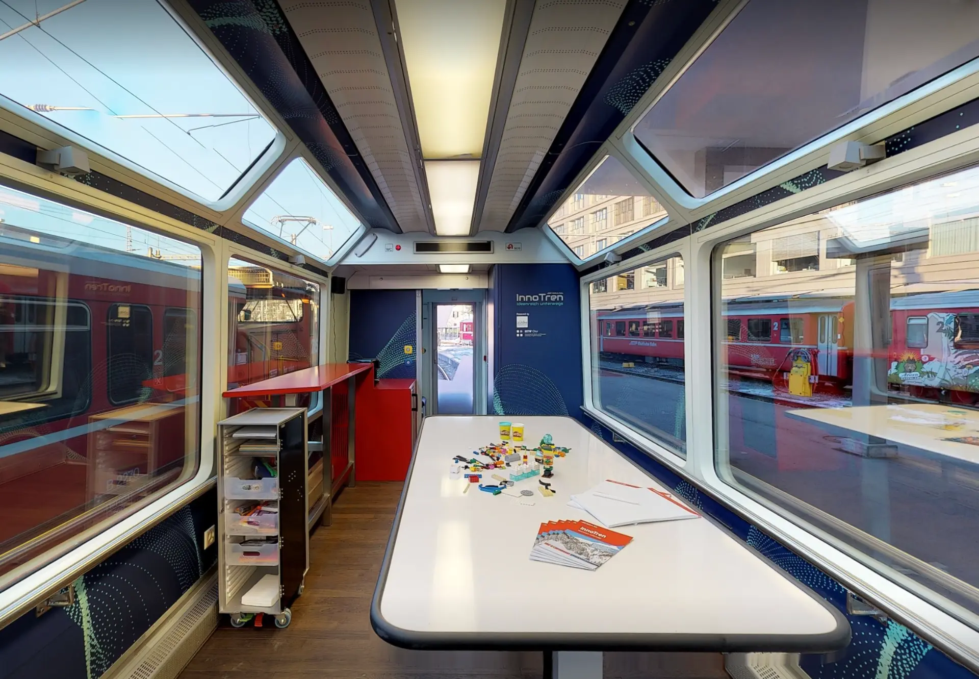 Panorama wagon in workshop layout with a long table, service trolley and a red bar counter