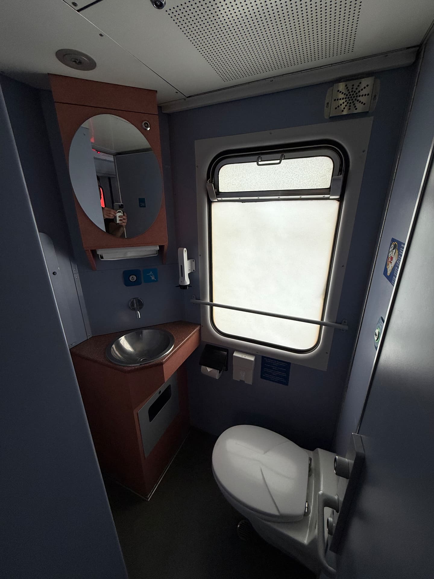 Indoor washroom aboard the train with basin, mirror and frosted window
