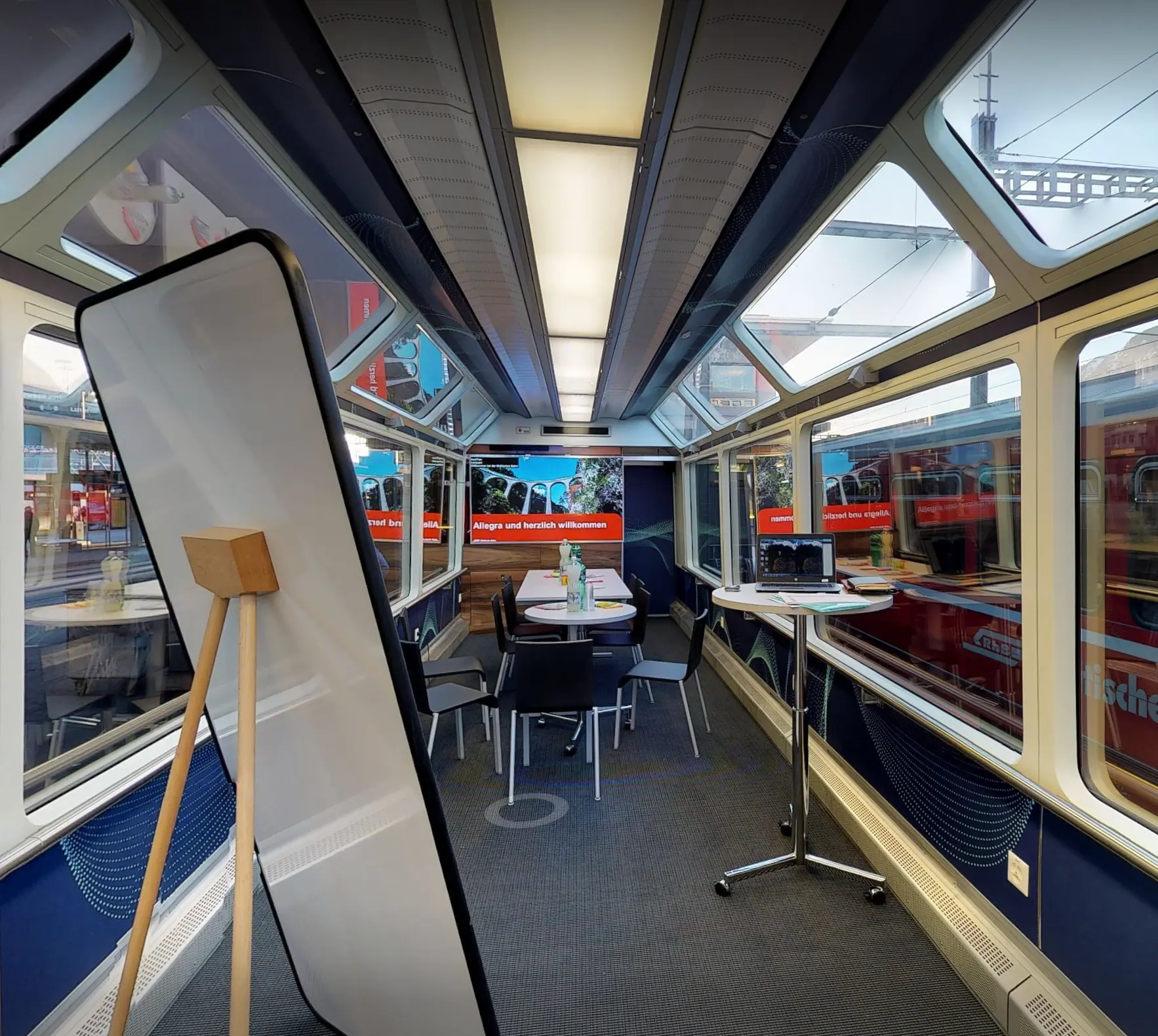 Panorama wagon with high tables, a flipchart, screen at the far end and glass roof windows